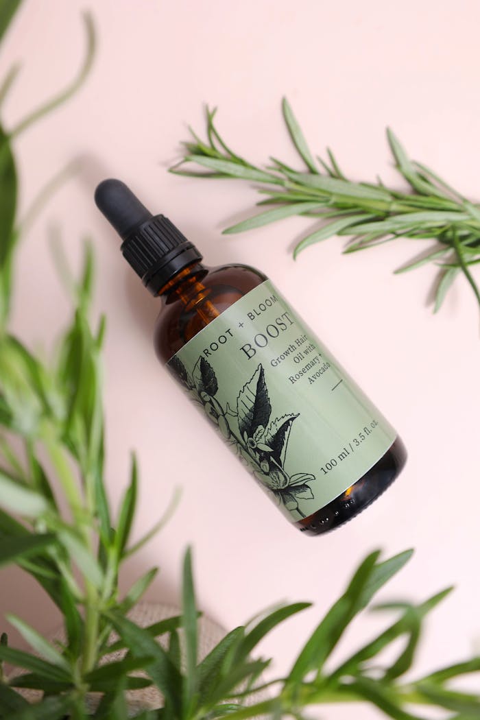 about-03 Natural hair growth oil in a glass bottle with botanical elements on a pastel background.