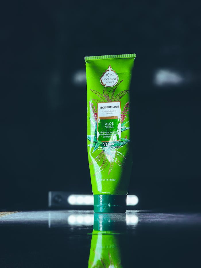 Close-up of aloe vera moisturizing conditioner bottle on reflective surface.