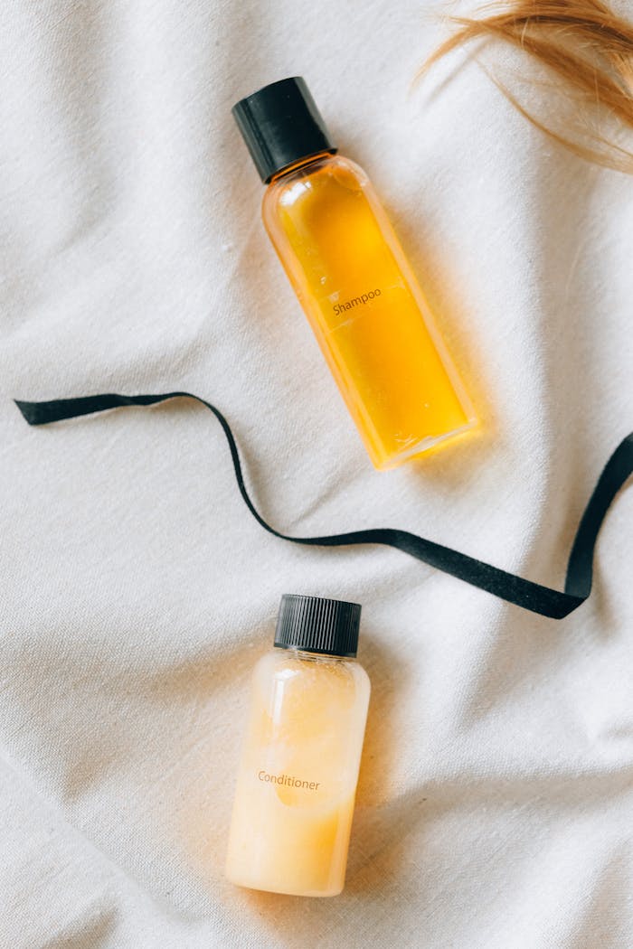 Flat lay of shampoo and conditioner bottles with a black ribbon on a textured fabric.